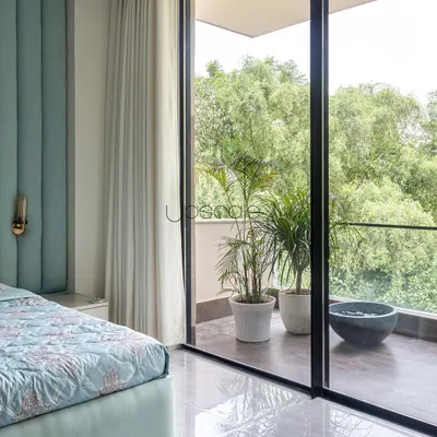 This bedroom was designed to feel like a retreat. The large, sliding glass door opens onto a private balcony, allowing the sights and sounds of the lush green outdoors to become a part of the room's serene atmosphere.