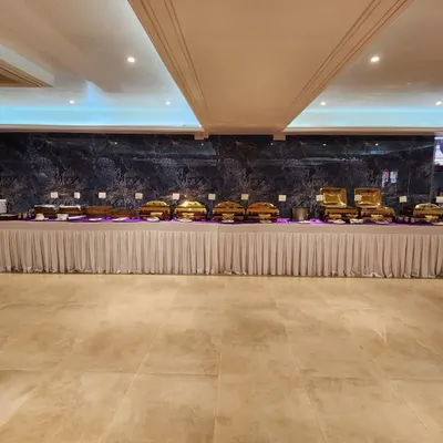 A wide view of a complete banquet setup in a spacious hall. The long, continuous buffet line with gleaming gold chafing dishes creates a grand and inviting look for any large scale event.
