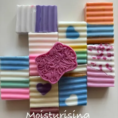 A beautiful collection of my moisturizing handmade soaps. You can see the variety of colors and designs, from layered bars to those with little hearts, all crafted to be gentle on the skin.