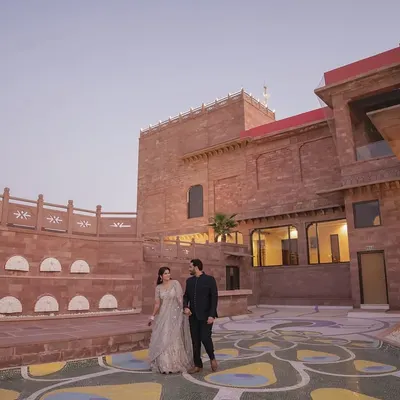 A magnificent wide shot of the couple in the courtyard of the Radisson Hotel Jodhpur. The grand scale of the heritage architecture provides a stunning, regal backdrop for their pre-wedding photos.