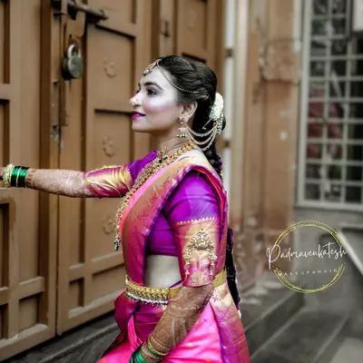 A beautiful side profile of a South Indian bride, showcasing the intricate hairstyle adorned with traditional hair jewelry and the flawless, glowing makeup that lasts through all the wedding rituals.