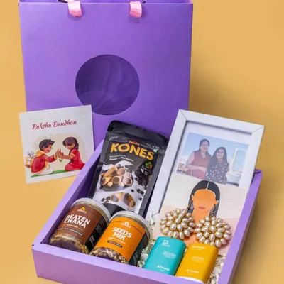 This Rakshabandhan hamper is a perfect example of a complete gift set. It includes a personalized photo frame, healthy snacks, traditional earrings, and a Rakhi card, all beautifully packed in a custom gift bag.