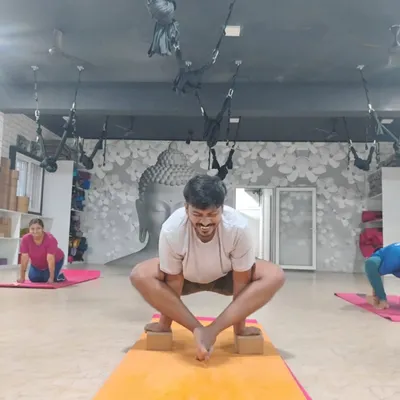 A student demonstrates focus and strength, using blocks for balance in a variation of Malasana (Garland Pose).
