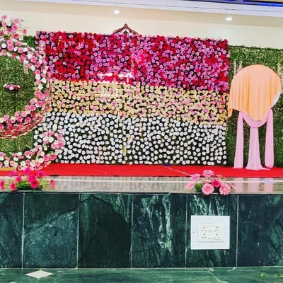 A grand stage decoration featuring a full floral wall and a greenery wall with a spiral floral design. This creates a stunning and multi-dimensional backdrop.