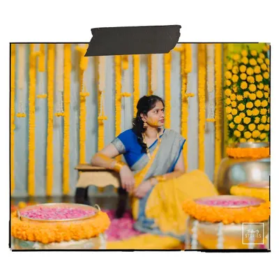 A candid shot of the bride during her Haldi ceremony, surrounded by marigold decorations, looking thoughtful and serene.