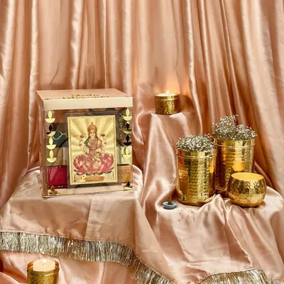 My Regal Festive Collection for Diwali, featuring a stunning acrylic box with a gold-plated Lakshmiji artwork. The hamper is surrounded by hammered gold candle holders, creating a warm, festive glow.