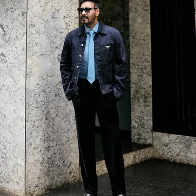 A full-length view of Ajay Devgn's Prada look, showing the perfect pairing of the denim jacket with black trousers and chunky dress shoes.