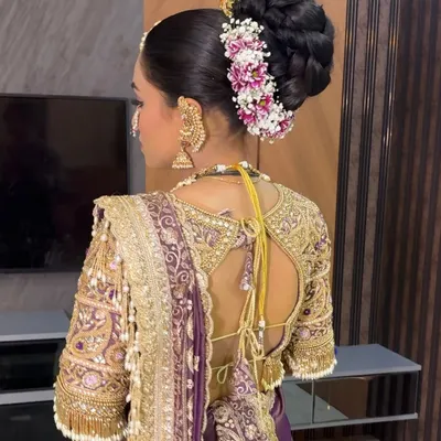 A close-up of a classic Maharashtrian bridal bun, intricately woven and adorned with fresh flowers and a pearl-studded pin.