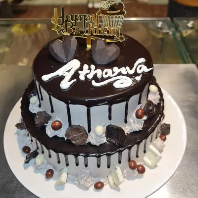 A decadent two-tier chocolate mousse cake. This rich cake is covered in chocolate ganache drips and topped with geometric chocolate hearts.