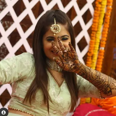 A happy bride playfully showing off her intricate bridal mehndi, her smile says it all.