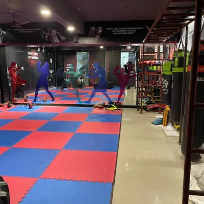 A view of my training facility in Noida. It features a large matted area, wall mirrors for technique correction, and a variety of punching bags for striking practice.
