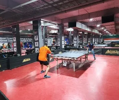 A wide shot of a match in progress during a corporate tournament. You can see the professional setup with multiple tables and ample space for players.