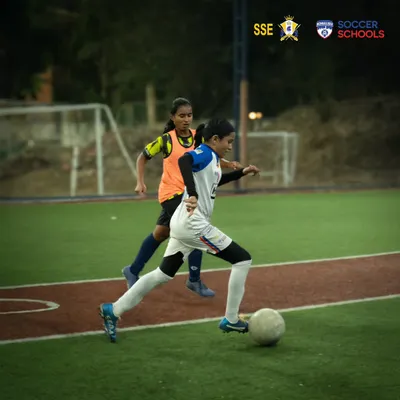 A player skillfully maneuvers the ball while being marked by a defender during a combined training session with Mumbai Knights. This competitive practice sharpens game-day performance.
