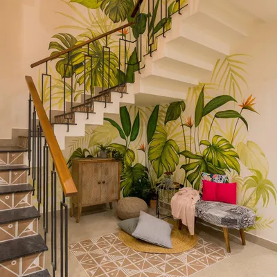 A cozy nook created under the staircase, brought to life by a vibrant, hand-painted tropical mural. This space, once overlooked, is now a beautiful and inviting corner for reading or relaxing.