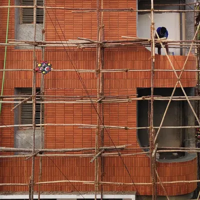 The 'Kutumb' project in progress. You can see the texture and pattern of the brick facade as it's being meticulously applied by artisans. The bamboo scaffolding is a traditional and sustainable method in itself.