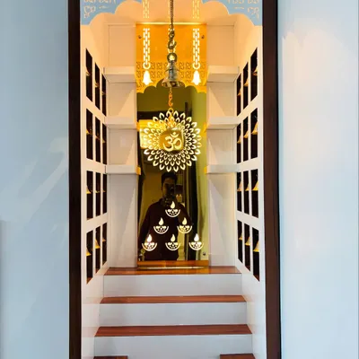 This is the interior of a custom pooja unit I designed. It features a mirrored back with an etched 'Om' and diya motifs, which are beautifully illuminated by internal lights. The stepped platform allows for multiple idols.