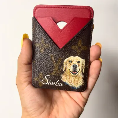 A custom hand-painted Louis Vuitton cardholder featuring a portrait of the client's dog, Simba. This is a perfect way to personalize your items and keep your loved ones close.