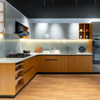 This spacious L-shaped kitchen beautifully marries warm wood base cabinets with sleek, light grey glossy uppers. The design includes open wicker basket drawers and an integrated oven unit, creating a perfect blend of natural textures and modern convenience.