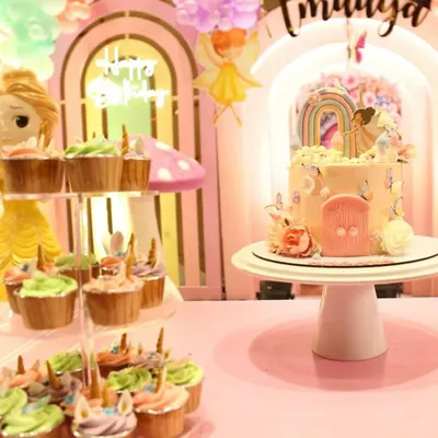 Here is a closer look at the "Wonderland" dessert table we created for Imaaya's birthday. The centerpiece cake, with its delicate fairy and rainbow topper, is perfectly complemented by a tiered stand of matching unicorn cupcakes.