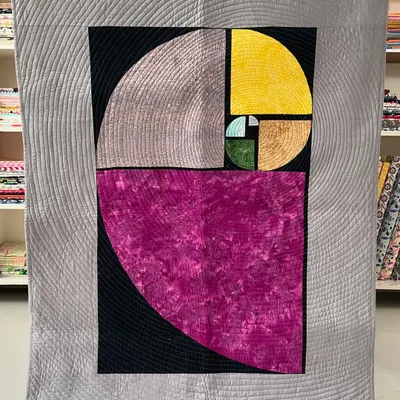 A magnificent art quilt depicting the Fibonacci spiral. The design is enhanced by quarter-inch spiral quilting that radiates outwards, creating a mesmerizing visual effect.