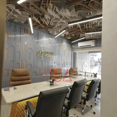 A wider perspective of the StyleIn Homes conference room, showing how the intricate ceiling, paneled wall with brand logo, and luxurious seating come together to create a powerful and professional meeting environment.