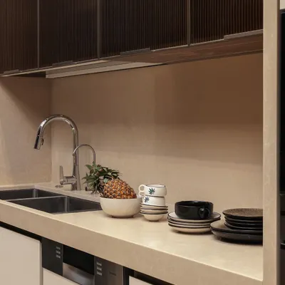 Styling turns the everyday into a curated moment. A touch of greenery, a bowl of fresh fruit, and perfectly stacked ceramics on the countertop add life and personality to this modern kitchen.