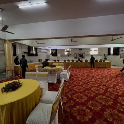 A full view of a banquet hall setup, showing our round table seating arrangement and a long buffet line in the background. We handle setups for large gatherings.