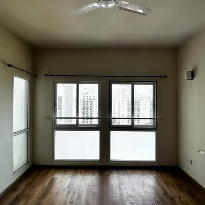 Before: An empty guest room in the 'Cover me in Sunshine' project, with standard windows and wooden flooring, waiting for a touch of warmth and functionality.