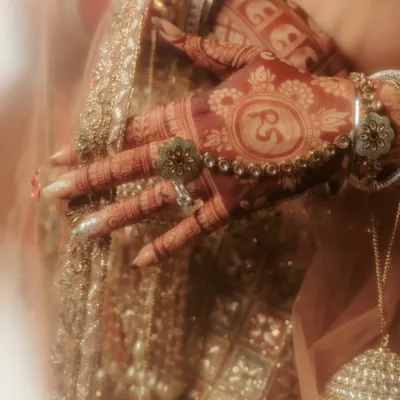 A close-up on the bride's hands, showcasing the beautiful, deep color of her henna and the custom initials 'RS' for Raghavi and Shivam, a personal touch I love to capture.