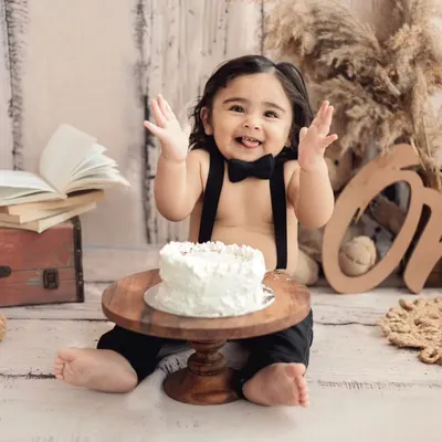 The best part of a cake smash? The pure, unfiltered happiness! This little traveler is enjoying his first taste of birthday cake in our rustic, globe-trotter themed setup.