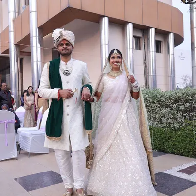 Make a grand entrance together. This couple looks absolutely regal, with him in a classic white sherwani with a contrasting green stole and her in a delicate white chikankari lehenga. A perfect look for a day wedding.