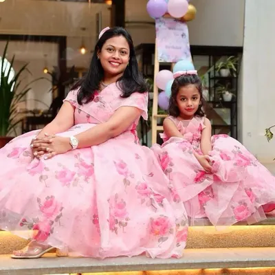 A happy client and her daughter posing in their matching pink floral gowns at a birthday party. The lightweight organza fabric makes these dresses comfortable for long events.