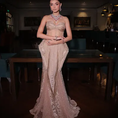 A full-length view of a bespoke champagne silk gown. The design features a structured corset bodice and a fish-cut skirt with intricate handwork, creating a silhouette that is both timeless and personal.