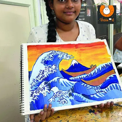 A student proudly holds up her painting of 'The Great Wave off Kanagawa'. We introduce young artists to famous artworks to inspire their own creations.