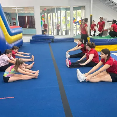Warming up is key! Our coaches lead a group of new students in essential stretches during our Open House event. Proper stretching is the first step to safe gymnastics.