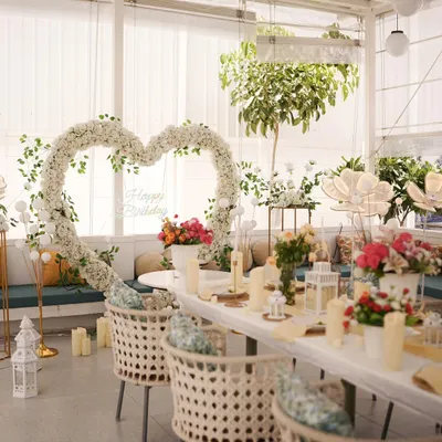 A bright and beautiful daytime celebration. The large white floral heart, fresh flowers, and elegant table setting create a perfect scene for a birthday lunch or anniversary brunch.