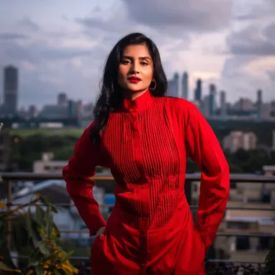 A powerful portrait from a rooftop photoshoot in Mumbai. The bold red outfit stands out against the city skyline, creating a striking and confident image.