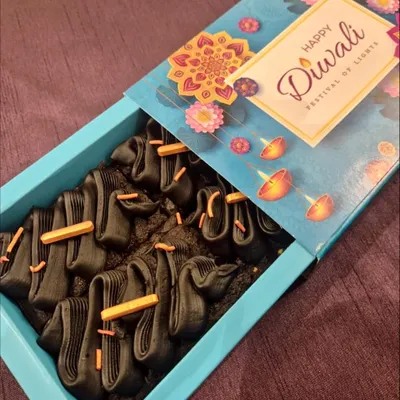 A box of my signature fudgy brownies, decorated with dark chocolate piping and sprinkles, presented in a beautiful "Happy Diwali" gift box. A perfect festive treat.
