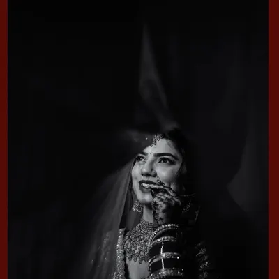 Behind the veil, a universe of emotions. This black and white portrait uses dramatic lighting to capture the bride's joyful, upward glance and the delicate details of her attire.
