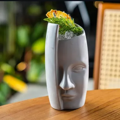 This cocktail is served in a custom ceramic glass shaped like a face, turning the drink itself into a piece of art. Sourcing unique glassware is a key part of my bar consulting service.