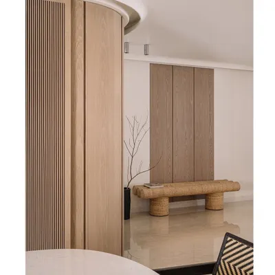 Welcome to Kanso House. The entrance features a curved wooden wall and a woven bench, immediately setting a tone of natural simplicity and calm.