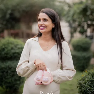A beautiful outdoor maternity portrait taken in a garden setting. The soft, natural light is perfect for creating a warm and gentle look, and the baby shoes add a sweet touch.