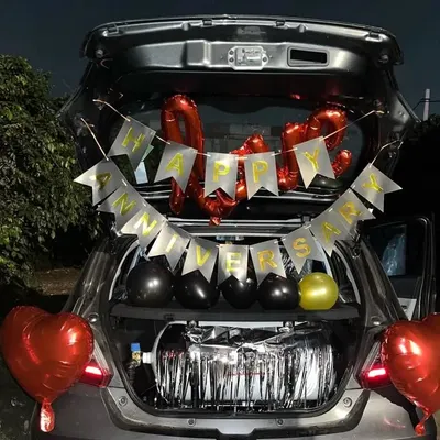 A 'Happy Anniversary' car boot decoration with red and black balloons and a silver fringe curtain.