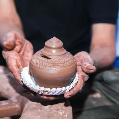 A master potter demonstrating how to shape clay on a wheel at our pottery station. Guests get to try their hand at creating their own small pot.