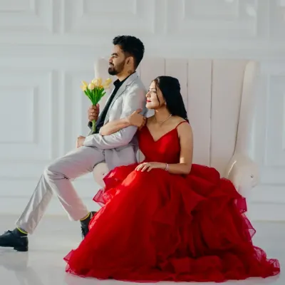 A picture-perfect moment. She is radiant in a classic red tiered ballgown, while he looks sharp in a light grey suit. This is the timeless, romantic look so many couples dream of.