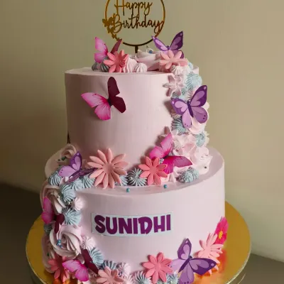 A gorgeous two-tier cake in shades of pink and purple, adorned with a cascade of butterflies and flowers.