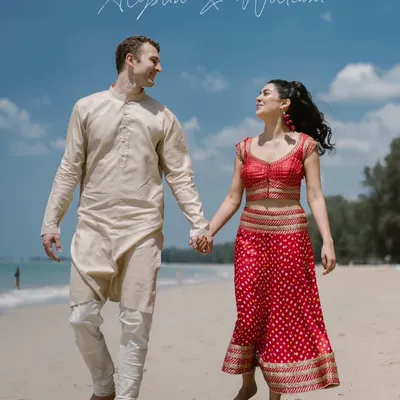 Hand in hand, walking towards forever on a Thai beach. This shot captures the simple romance of a destination wedding, where the couple's traditional Indian attire contrasts beautifully with the sand and sea.