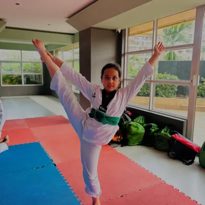 A student demonstrates a standing side split, a testament to the incredible flexibility we build in our classes.