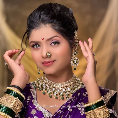 A classic Maharashtrian bridal portrait in a stunning purple saree. The focus here is on flawless skin, soft shimmery eyes, and traditional jewelry like the nath and chandrakor bindi to complete the look.