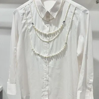 A standout piece from my collection, this opulent Swiss cotton shirt is adorned with hand-draped pearl chains. It’s a perfect example of how I transform a classic shirt into a piece of wearable art.